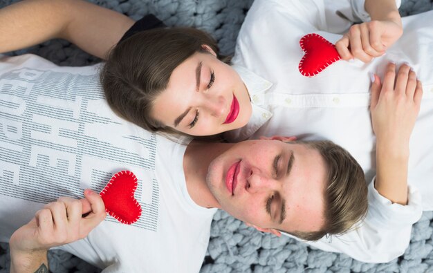 Pareja acostada con corazones de juguete pequeño