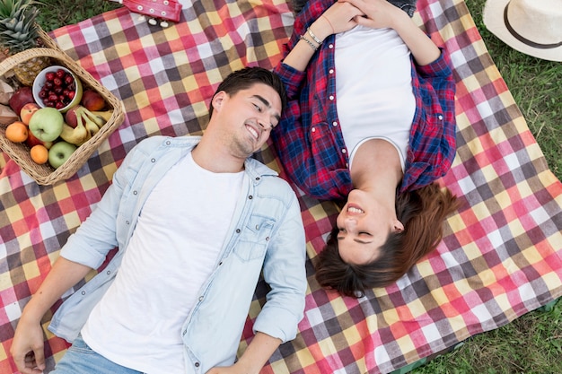 Foto gratuita pareja acostada en una manta de picnic vista superior