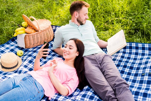 Pareja acostada en picnic a cuadros y relajante