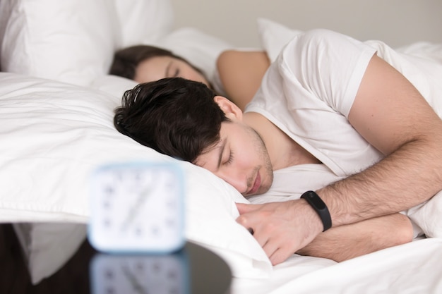 Pareja acostado dormido en la cama, hombre llevaba pulsera reloj inteligente