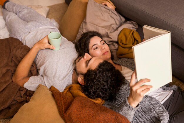 Pareja, acostado, juntos, en el sofá, mientras, lectura