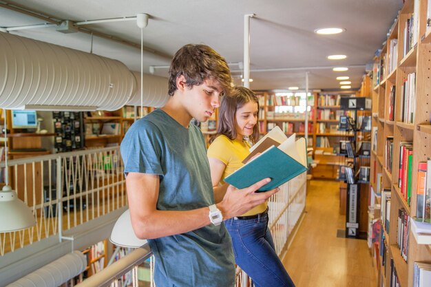 Pareja adolescente disfrutando de lectura cerca de barandilla