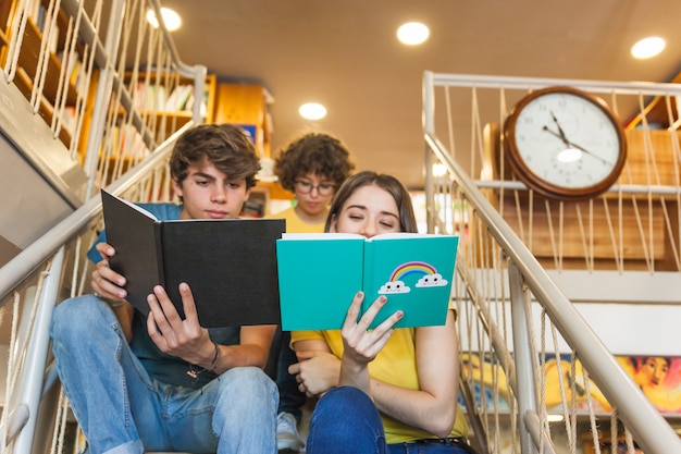 Pareja adolescente estudiando en pasos de la biblioteca