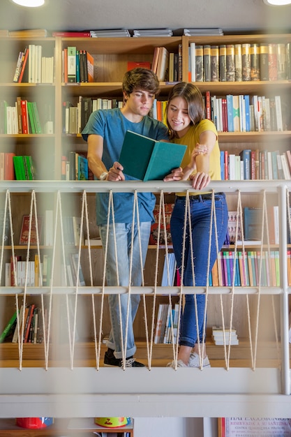 Foto gratuita pareja adolescente leyendo en el balcón de la biblioteca