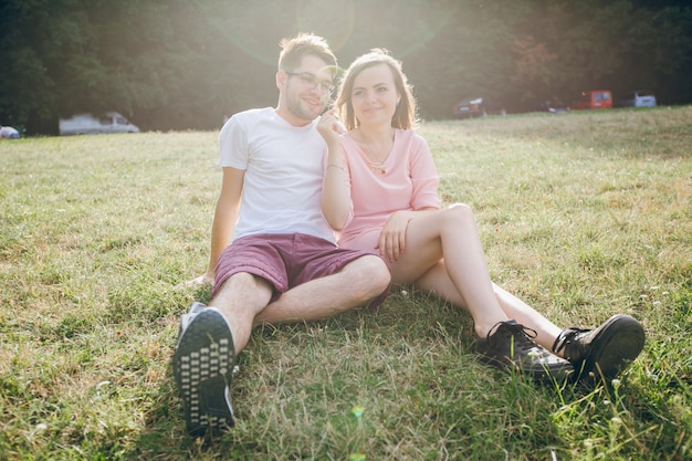 Pareja adorable sentada junta en el césped de un parque