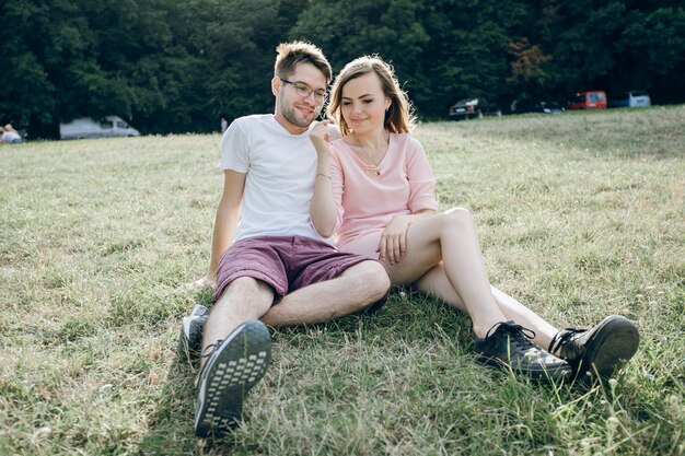 Pareja adorable sentada junta en el césped de un parque