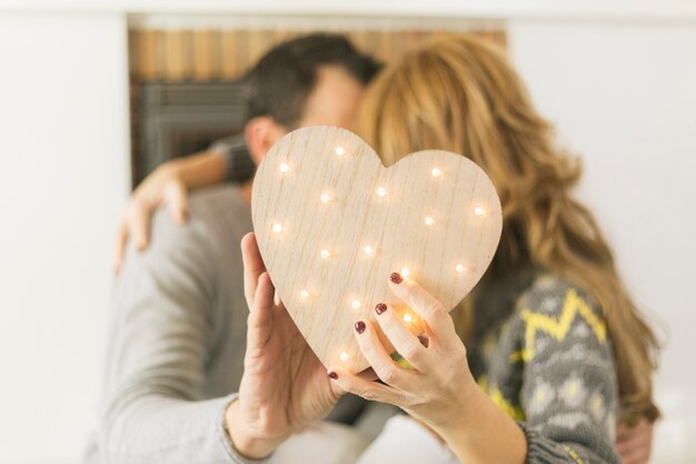 Pareja adulta besándose y cubriendo con corazón