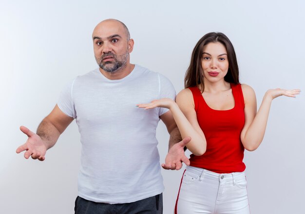 Pareja adulta confundida mirando el uno al otro y mostrando las manos vacías