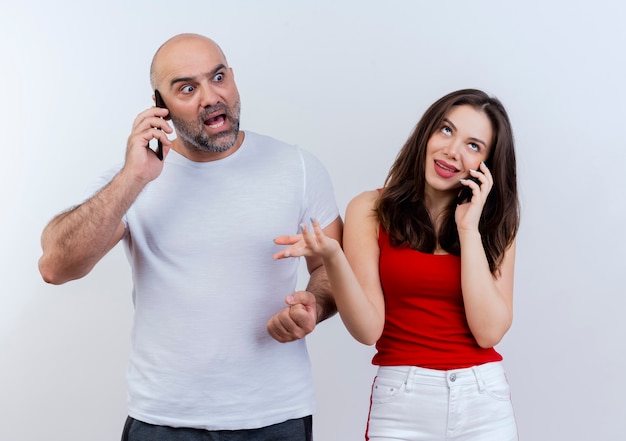 Foto gratuita pareja adulta hablando por teléfono impresionado hombre mirando al lado y mujer despistada mirando hacia arriba