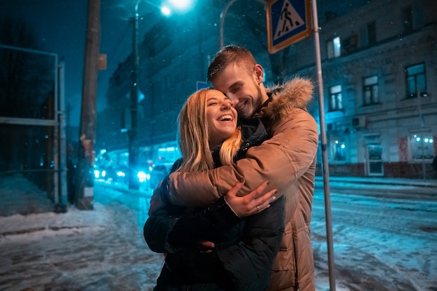 Pareja adulta joven caminando sobre la acera cubierta de nieve