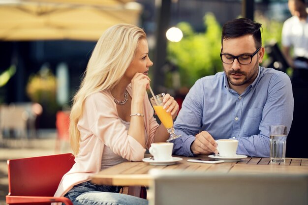 Pareja adulta media relajándose en un café y hablando entre ellos