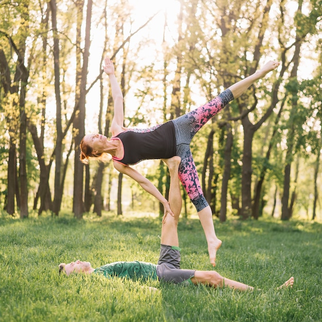 Foto gratuita pareja adulta media sana practicando acro yoga en pasto