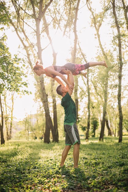 Pareja adulta media utilizando trucos acrobáticos en el parque