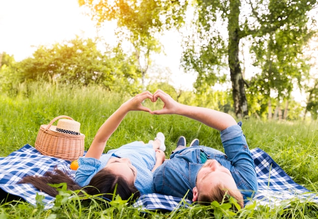 Pareja adulta multirracial haciendo signo de corazón con los dedos