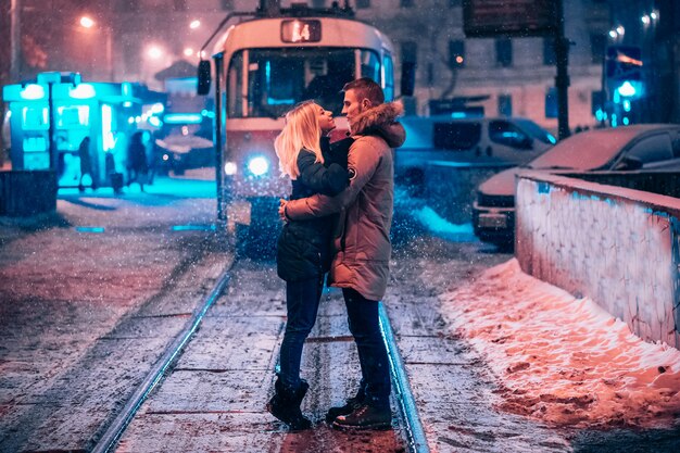 Pareja de adultos jóvenes en la línea de tranvía cubierto de nieve