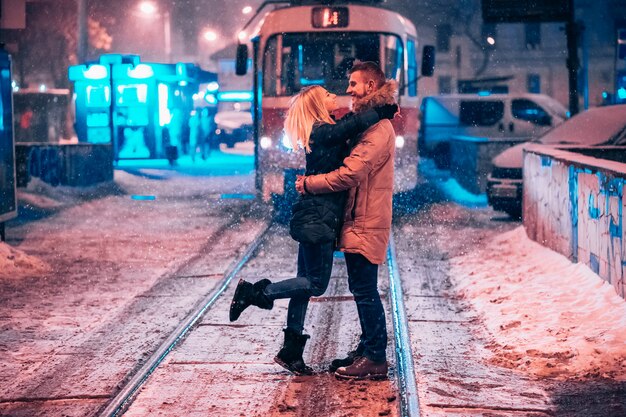 Pareja de adultos jóvenes en la línea de tranvía cubierto de nieve