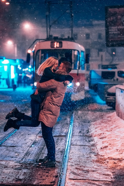 Pareja de adultos jóvenes en la línea de tranvía cubierto de nieve