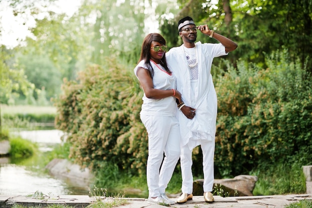 Pareja africana rica en vestido nacional blanco y gafas de sol