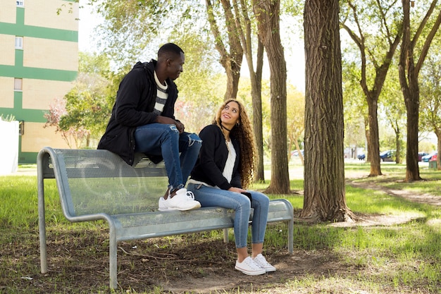 Pareja afro americana en banco en parque