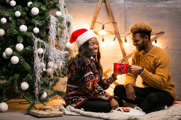 Pareja afroamericana, bebida, café, por el árbol de navidad