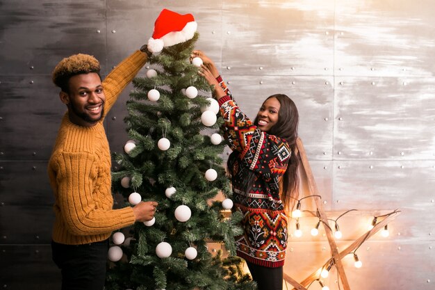 Pareja afroamericana colgando juguetes en un árbol de Navidad