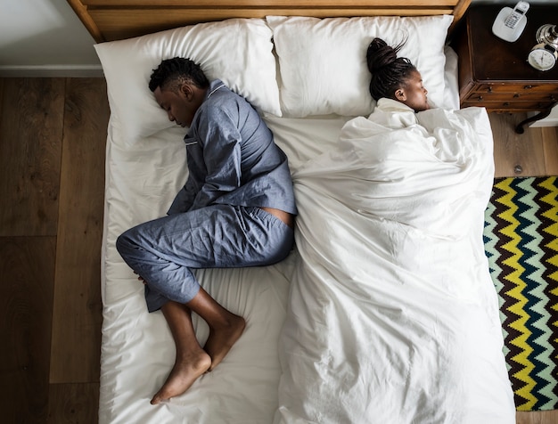 Pareja afroamericana durmiendo espalda contra espalda