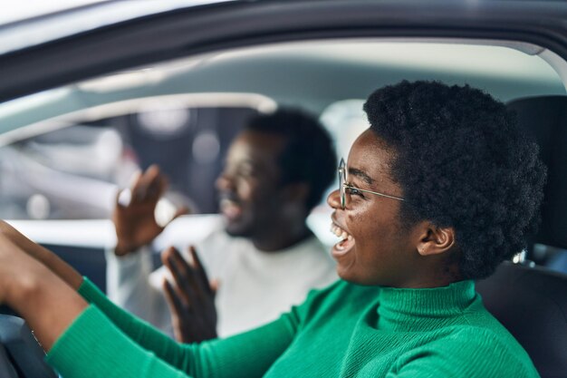 Pareja afroamericana de hombre y mujer conduciendo coche en la calle