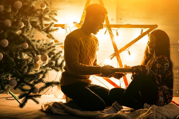 Pareja afroamericana sentada junto al árbol de Navidad