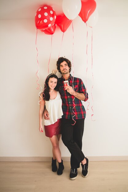 Pareja agarrada de la cintura con globos alrededor