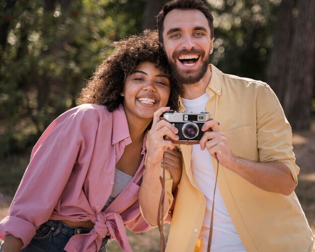 Pareja al aire libre sosteniendo y tomando fotografías con cámara