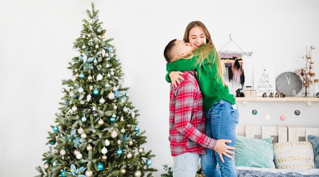 Pareja al lado de árbol de navidad en dormitorio