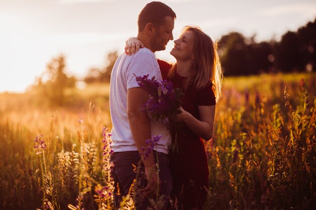 La pareja alegre se abraza oferta que se opone en el campo verde