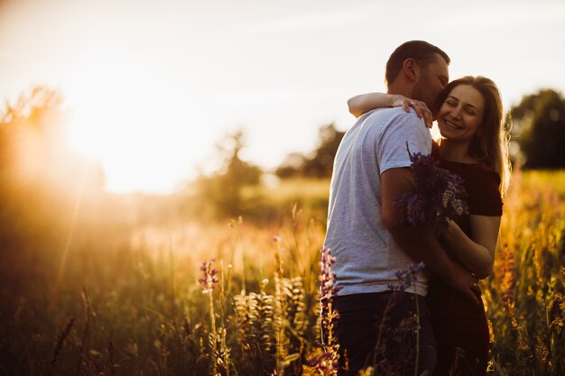 La pareja alegre se abraza oferta que se opone en el campo verde