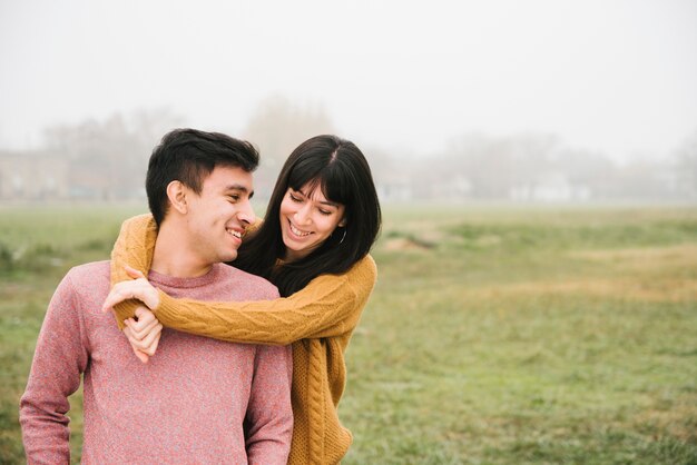 Pareja alegre abrazando en campo