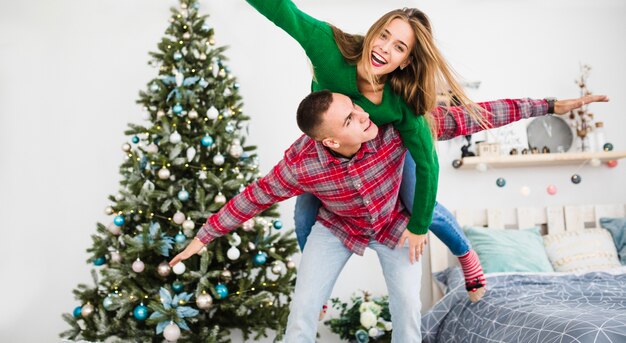 Pareja alegre al lado de árbol de navidad