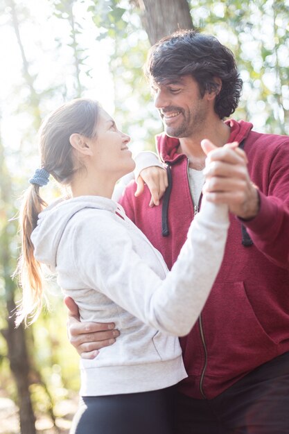 Pareja alegre bailando en el bosque