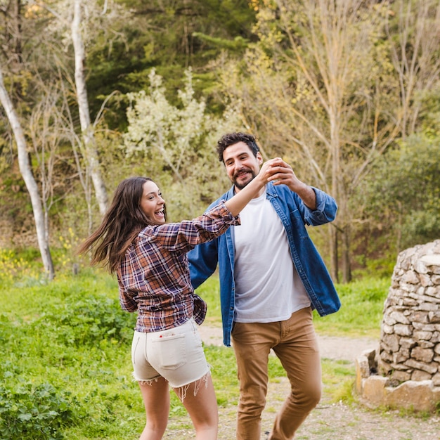 Pareja alegre bailando en la naturaleza