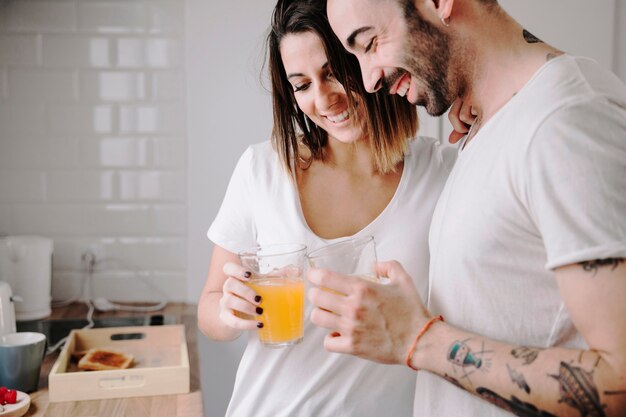 Pareja alegre beber jugo en la cocina