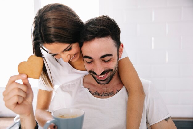 Pareja alegre con bebida y galletas