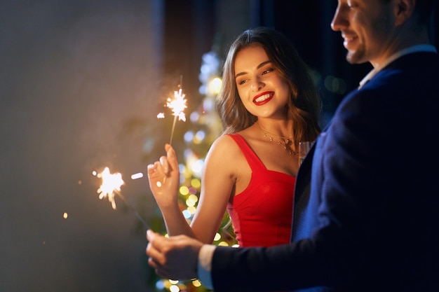 Pareja alegre con bengalas y bebiendo champán