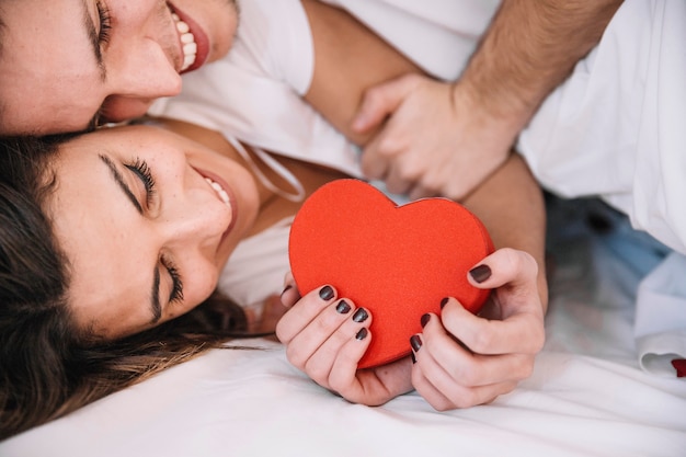 Pareja alegre con caja en forma de corazón