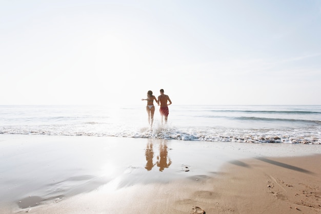 Foto gratuita pareja alegre corriendo en la orilla