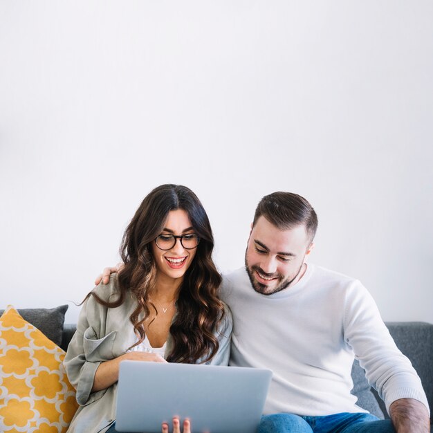 Pareja alegre con el cuaderno en el sofá