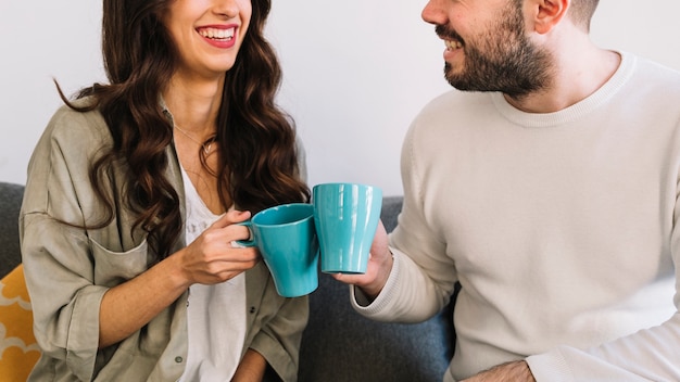 Pareja alegre de cultivos con tazas