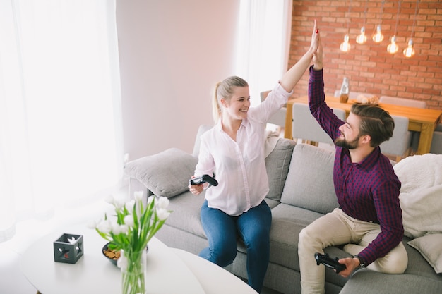 Pareja alegre con gamepads dando alta cinco