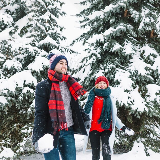 Pareja alegre jugando en el bosque de invierno