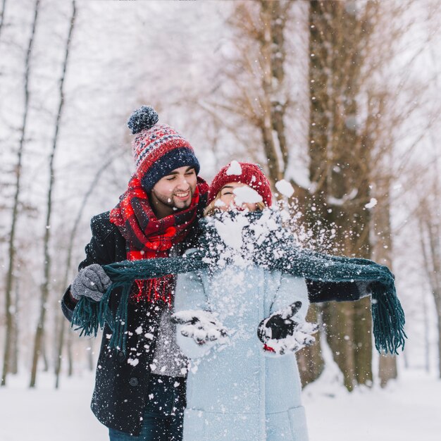 Pareja alegre jugando con nieve