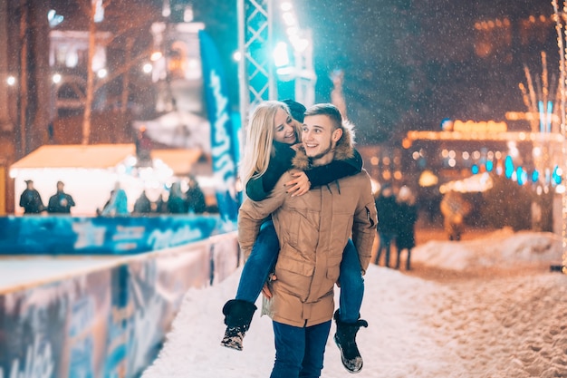 Pareja alegre y juguetona en trajes cálidos de invierno está jugando