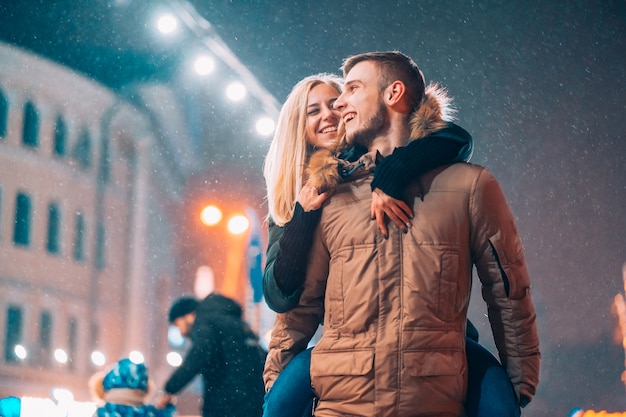 Pareja alegre y juguetona en trajes cálidos de invierno está jugando