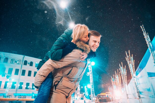 Pareja alegre y juguetona en trajes cálidos de invierno está jugando